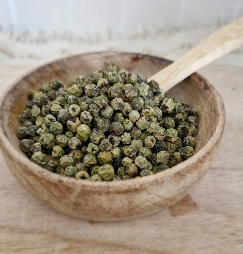 Poivre vert en grain dans une coupole en bois avec une cuillère