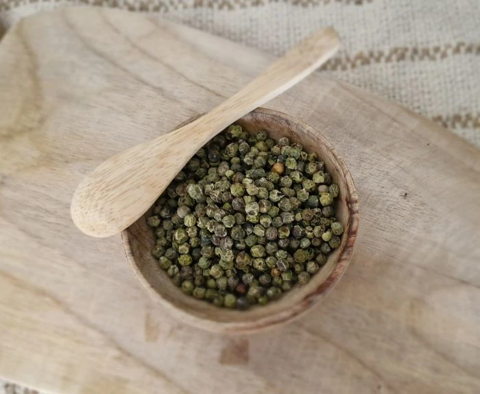Poivre vert en grain de dessus dans une coupole en bois avec une cuillère