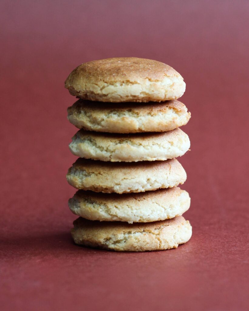 Des gâteaux basques moelleux et épais. Ils sont empilés de face sur un plan rouge clair